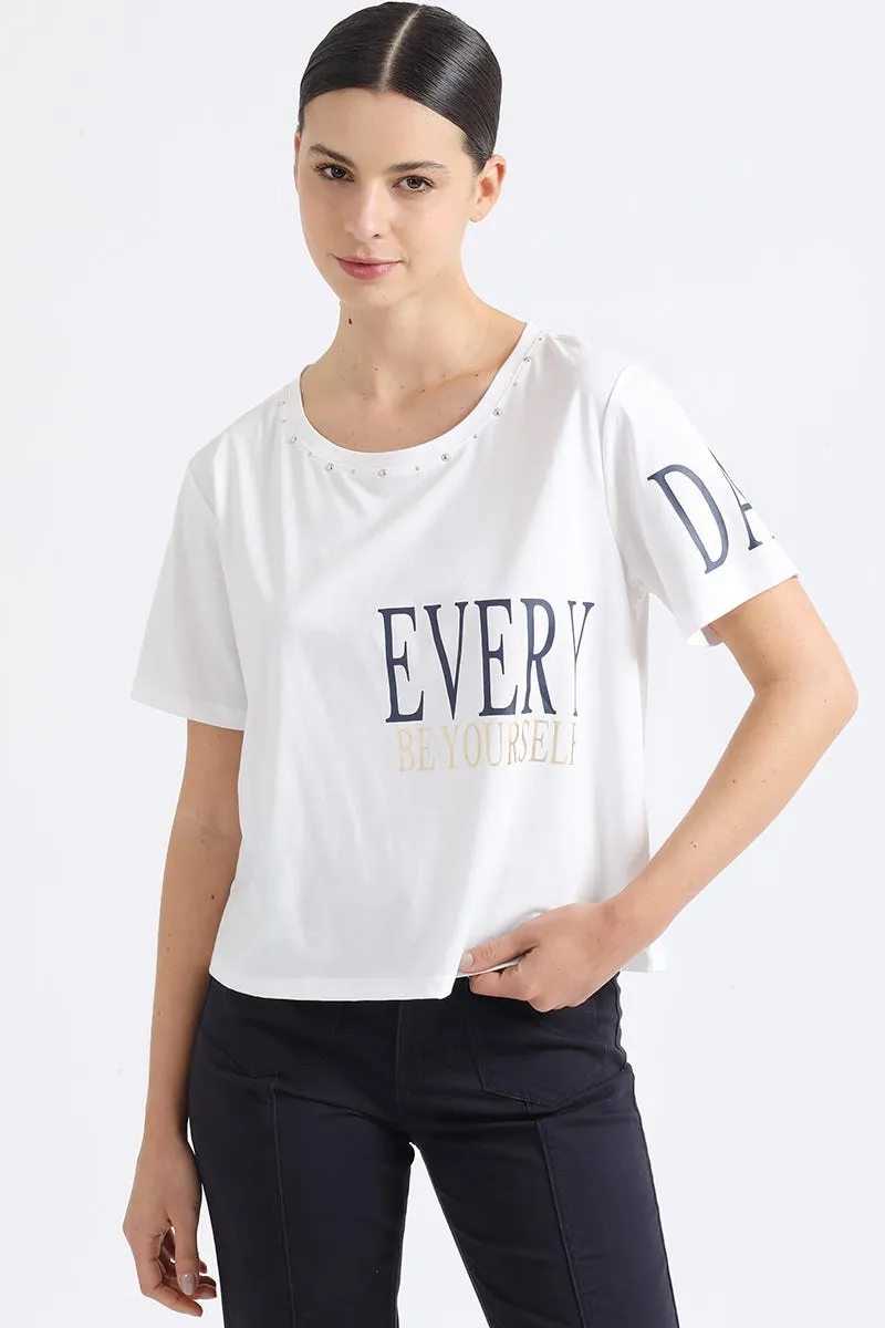 POLERA APLICACIÓN TACHAS Y ESTAMPADO TEXTO, CRUDO